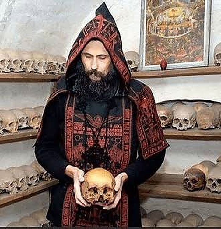 A monk in the ossuary, holding a brother's skull